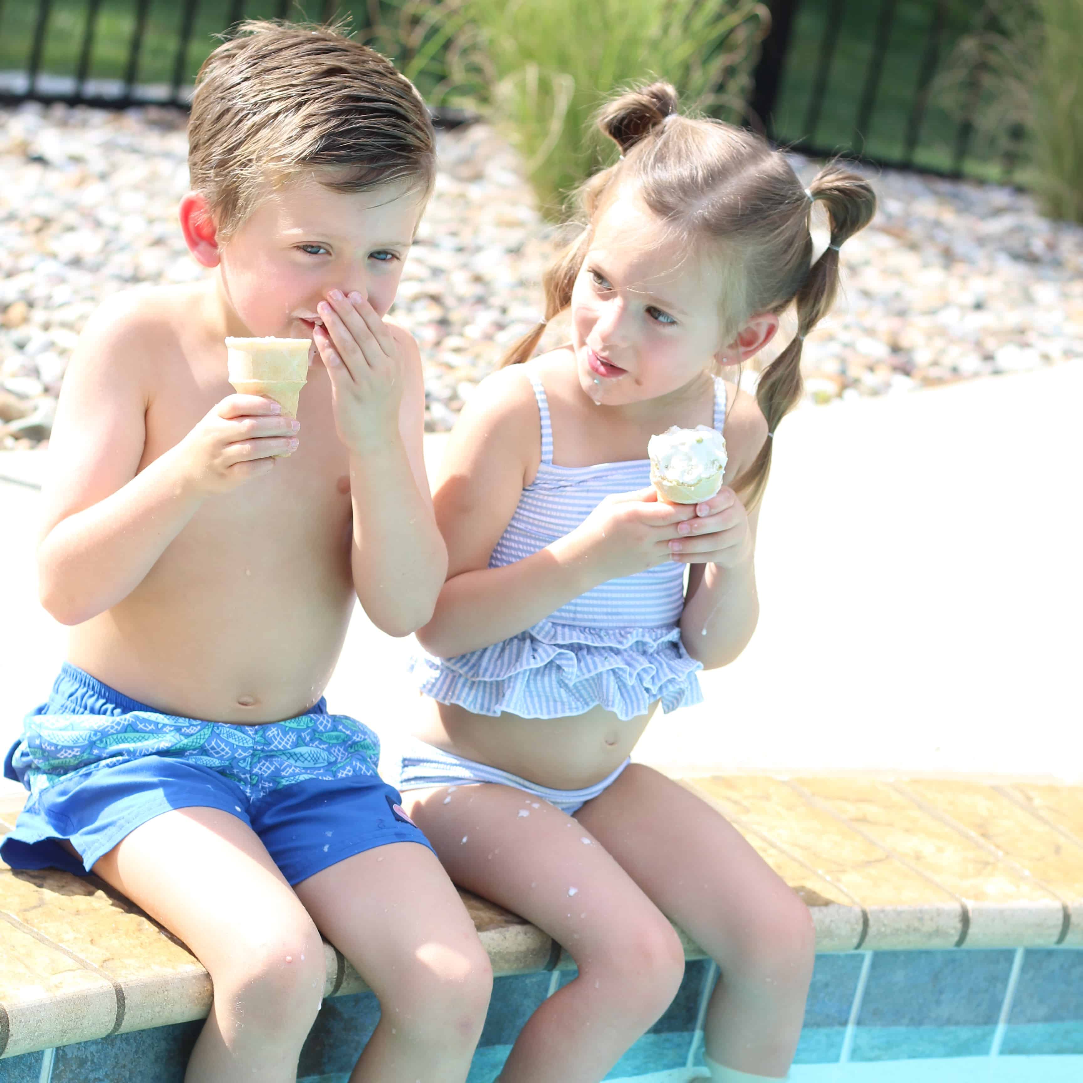 Two kids pool side eating ice-cream cones!