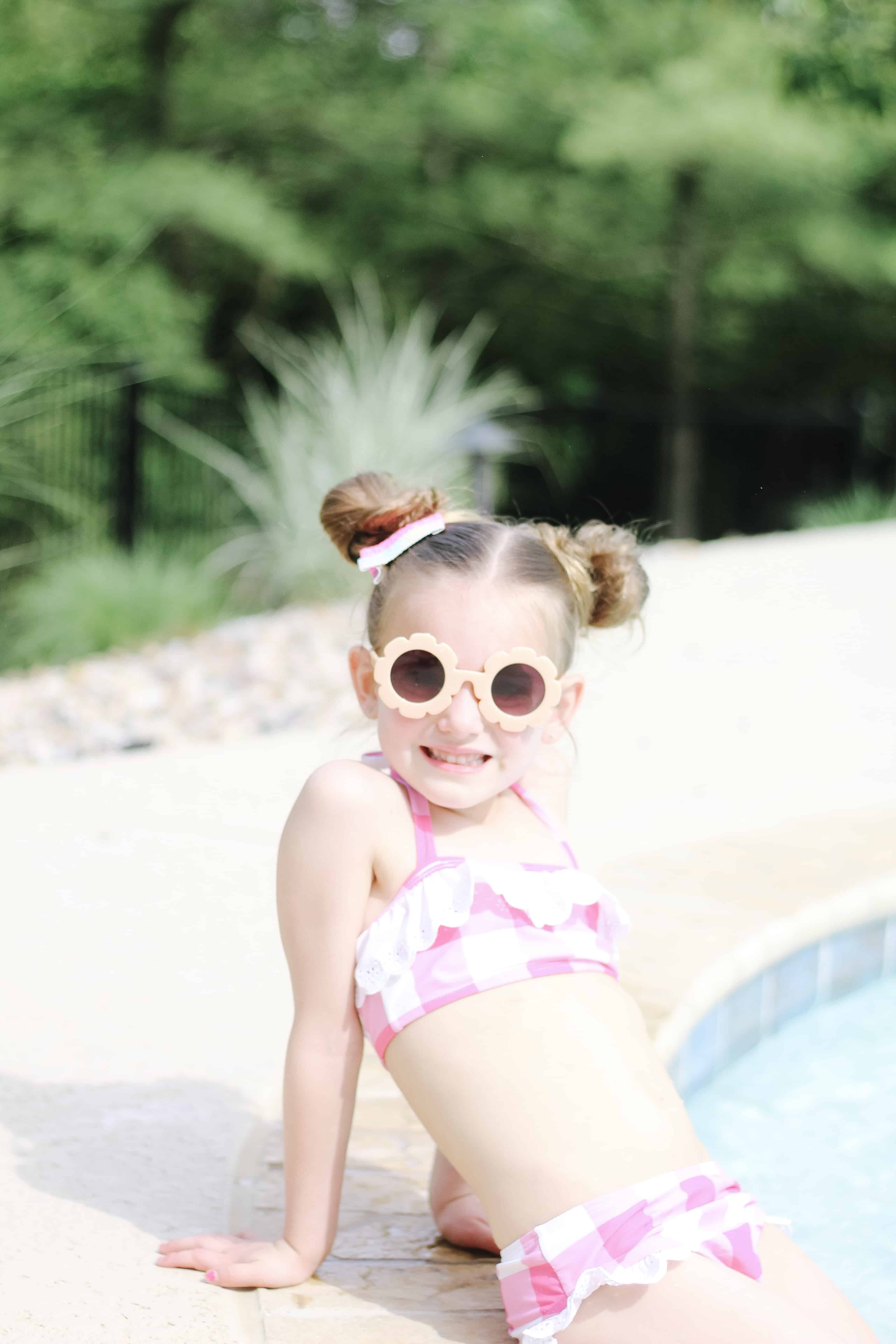 Toddler girl in flower sunglasses by pool
