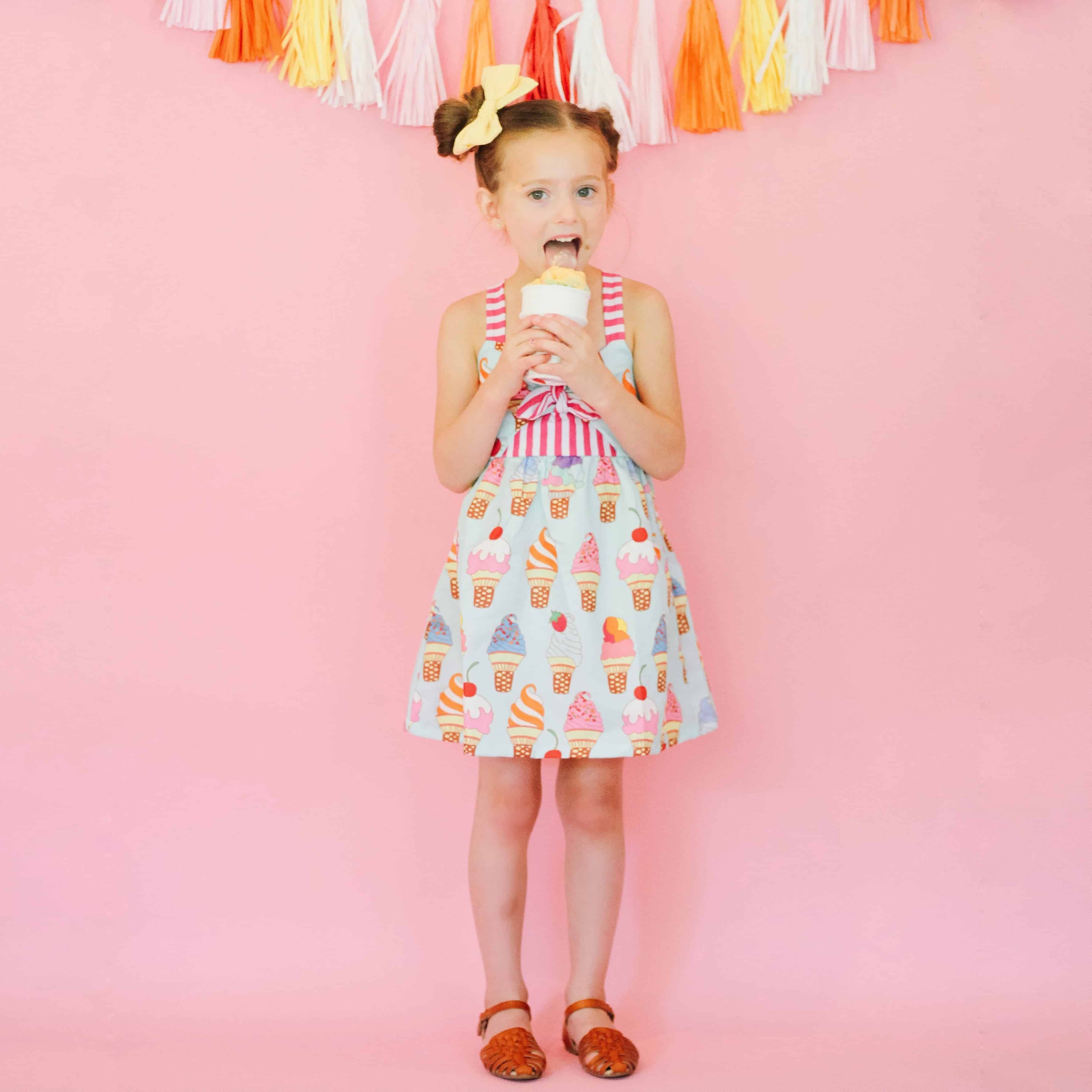 Little girl in ice cream dress against pink wall