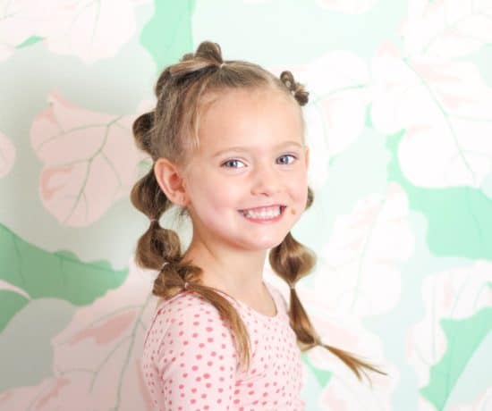 Little girl with bubble braid hair against green floral wall