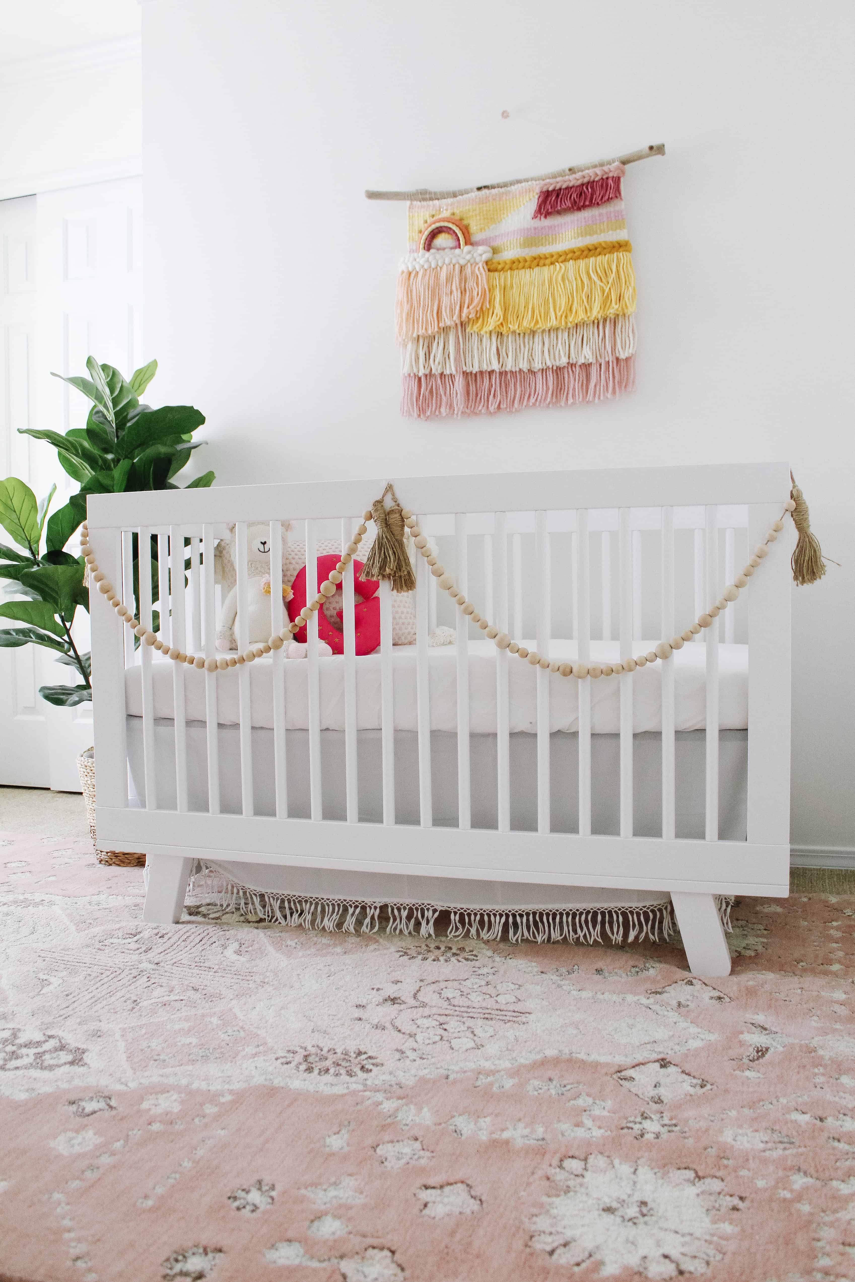 White crib with pink boho accents