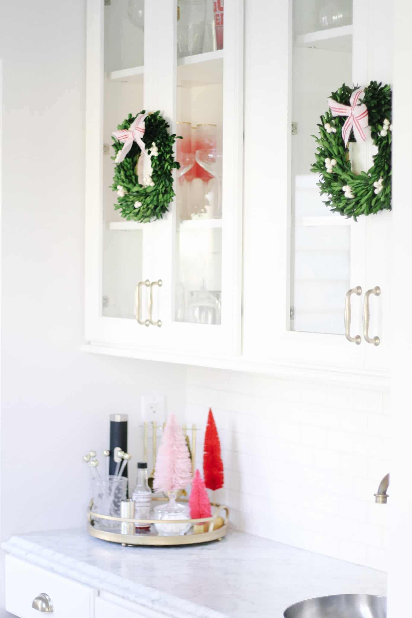 Boxwood wreaths on white kitchen cabinets