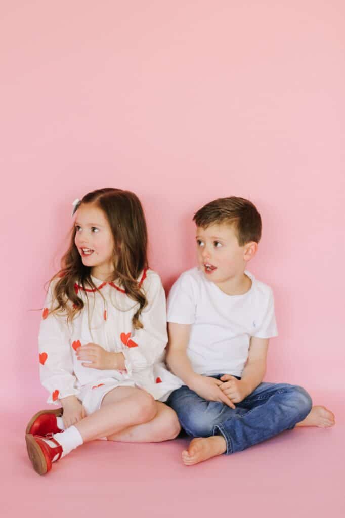 Toddlers dressed for valentines day  against pink backdrop