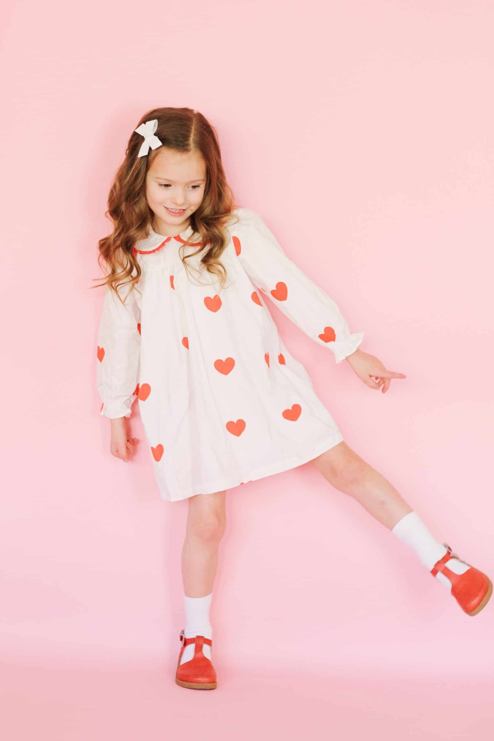 Toddler girl in white heart dress and red freshly picked Mary Janes