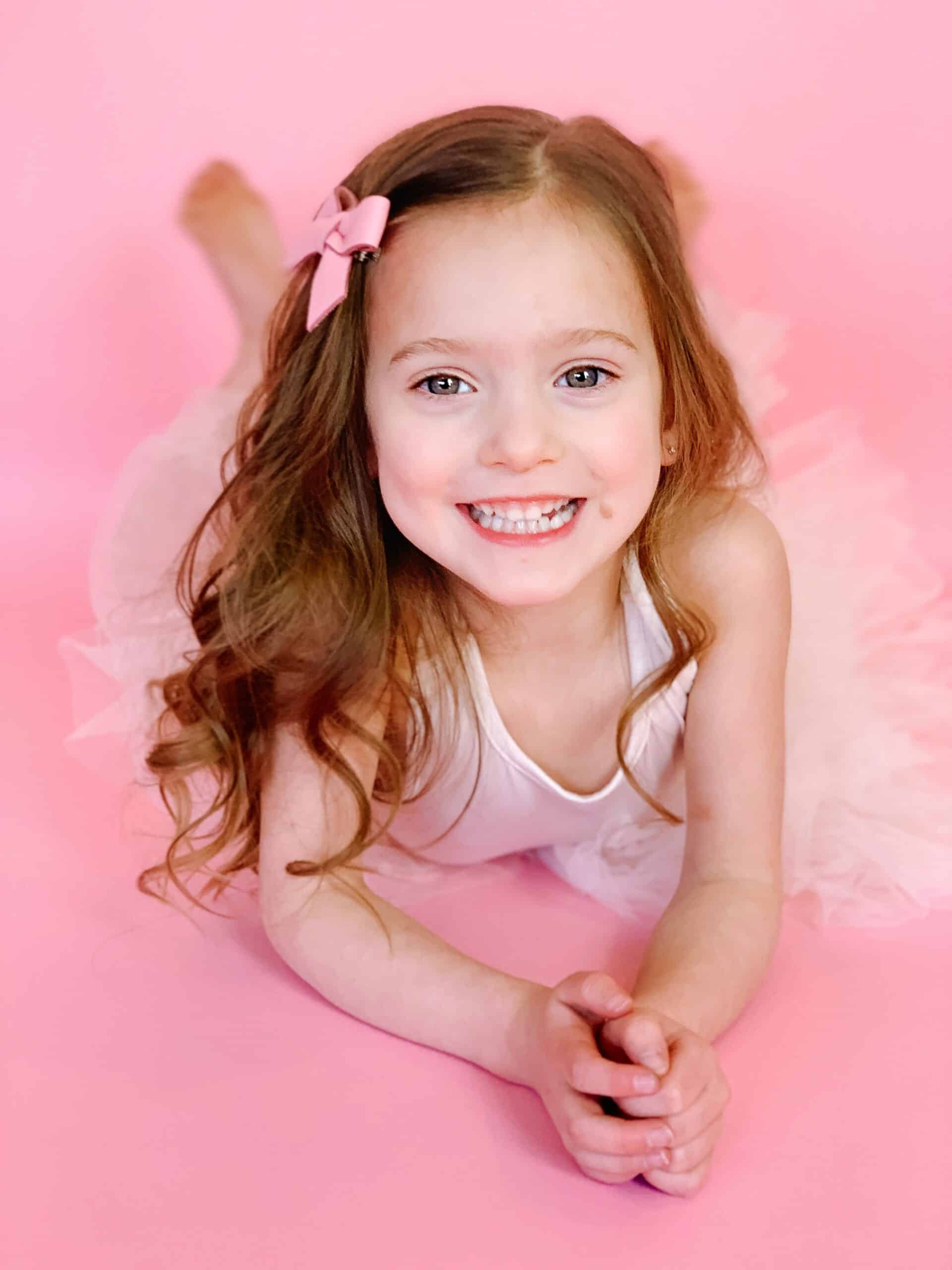 Toddler girl in white plum tutu on pink backdrop