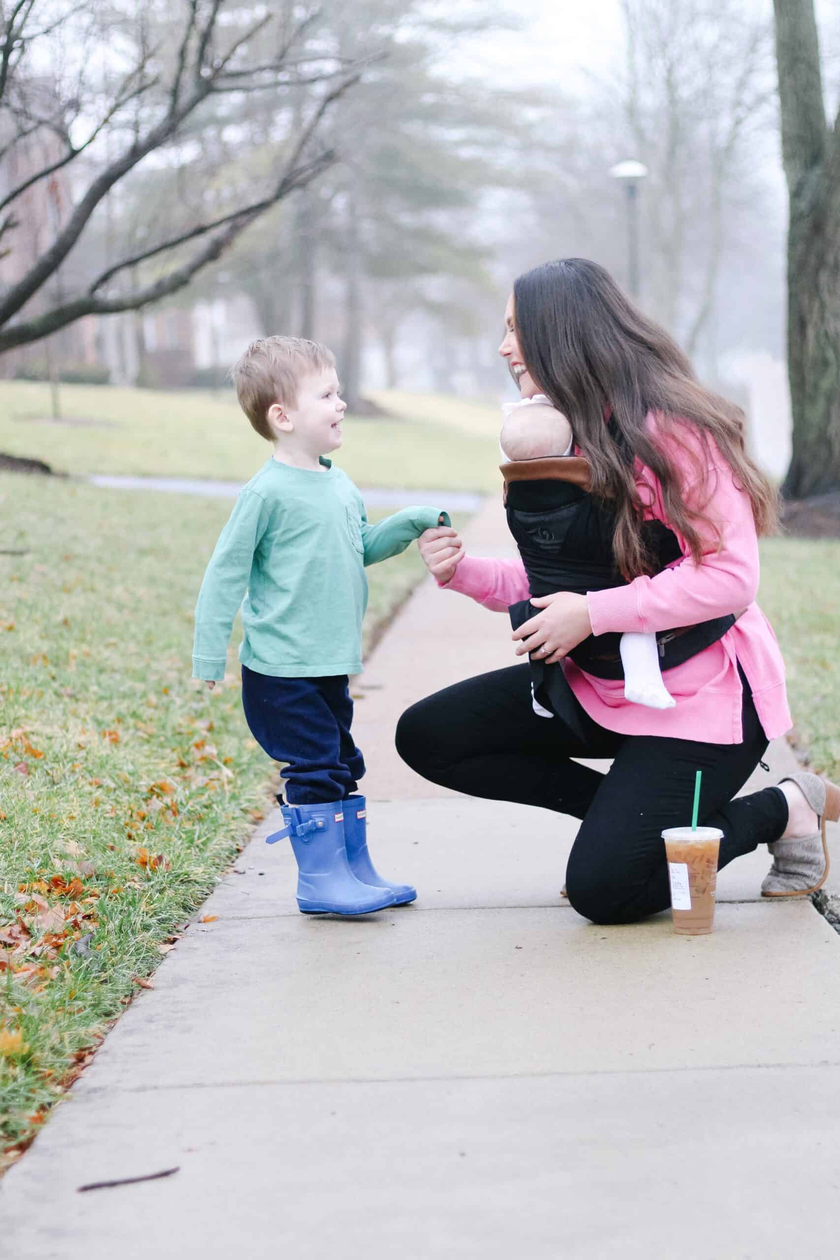 mom and toddler boy with baby in baby carrier