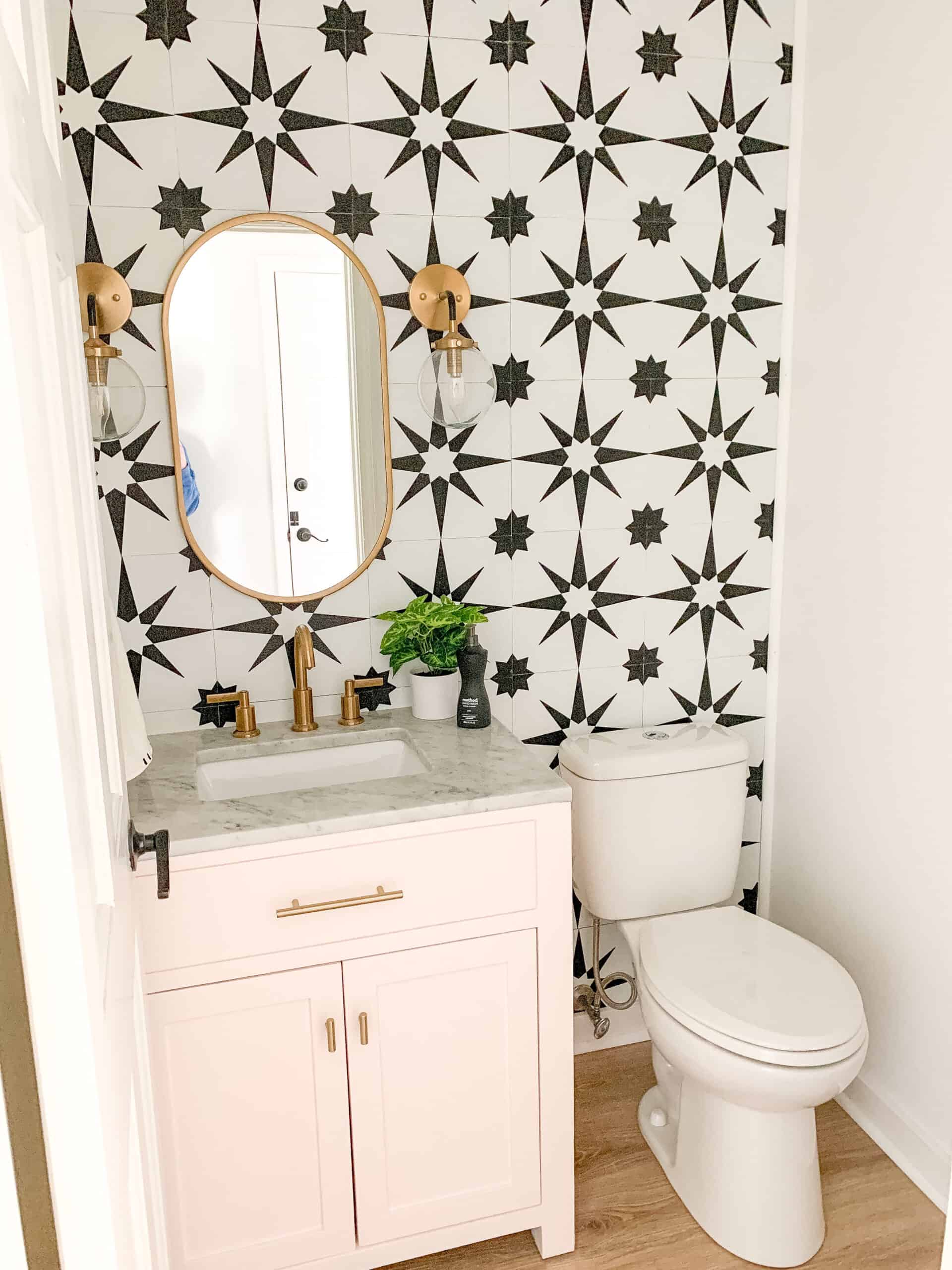 Blush pink powder room vanity with black and white tile wall