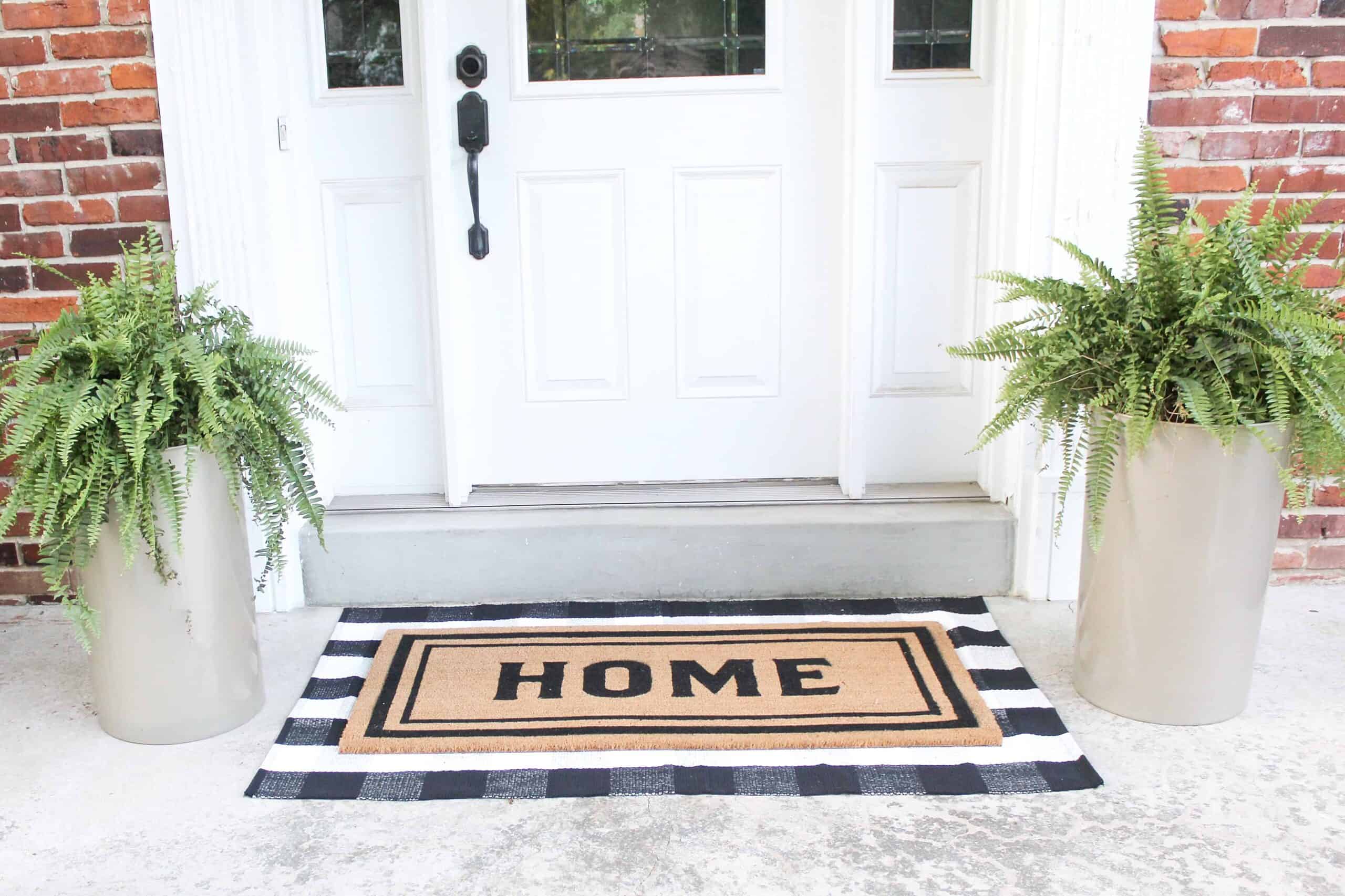front porch with gold planters and layered doormats