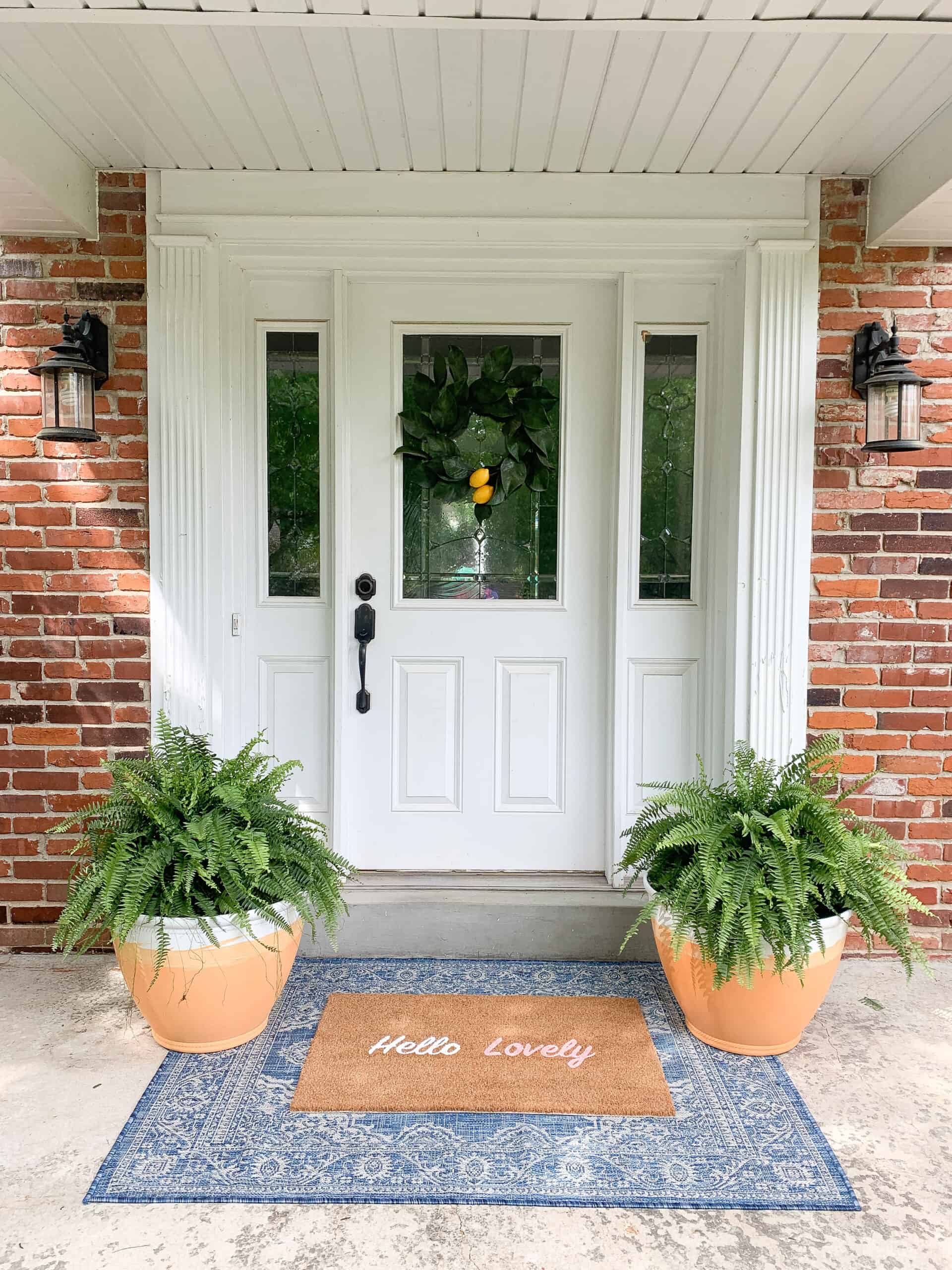 front porch with blue rug and terra-cotta planters