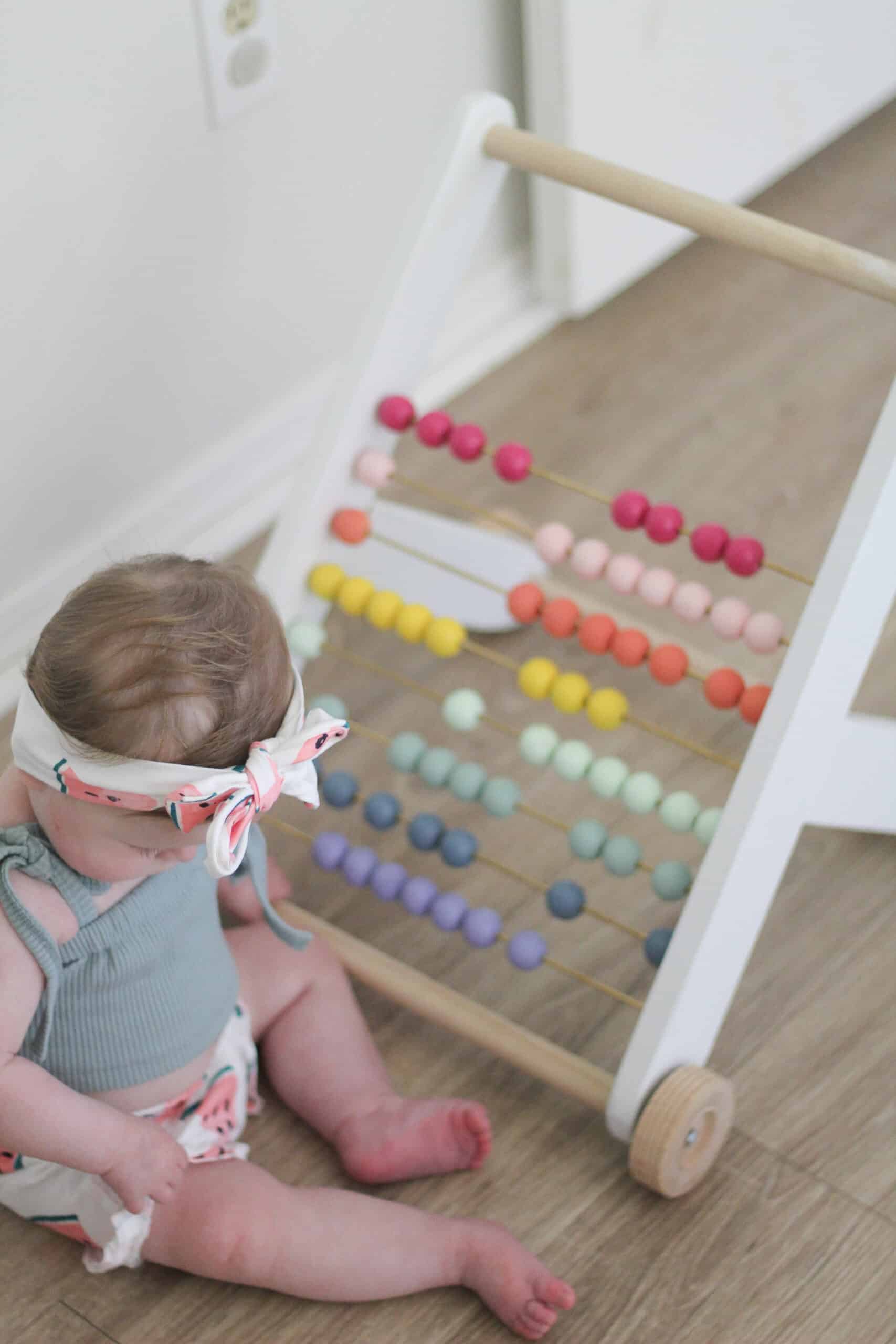 baby girl with rainbow push toy 