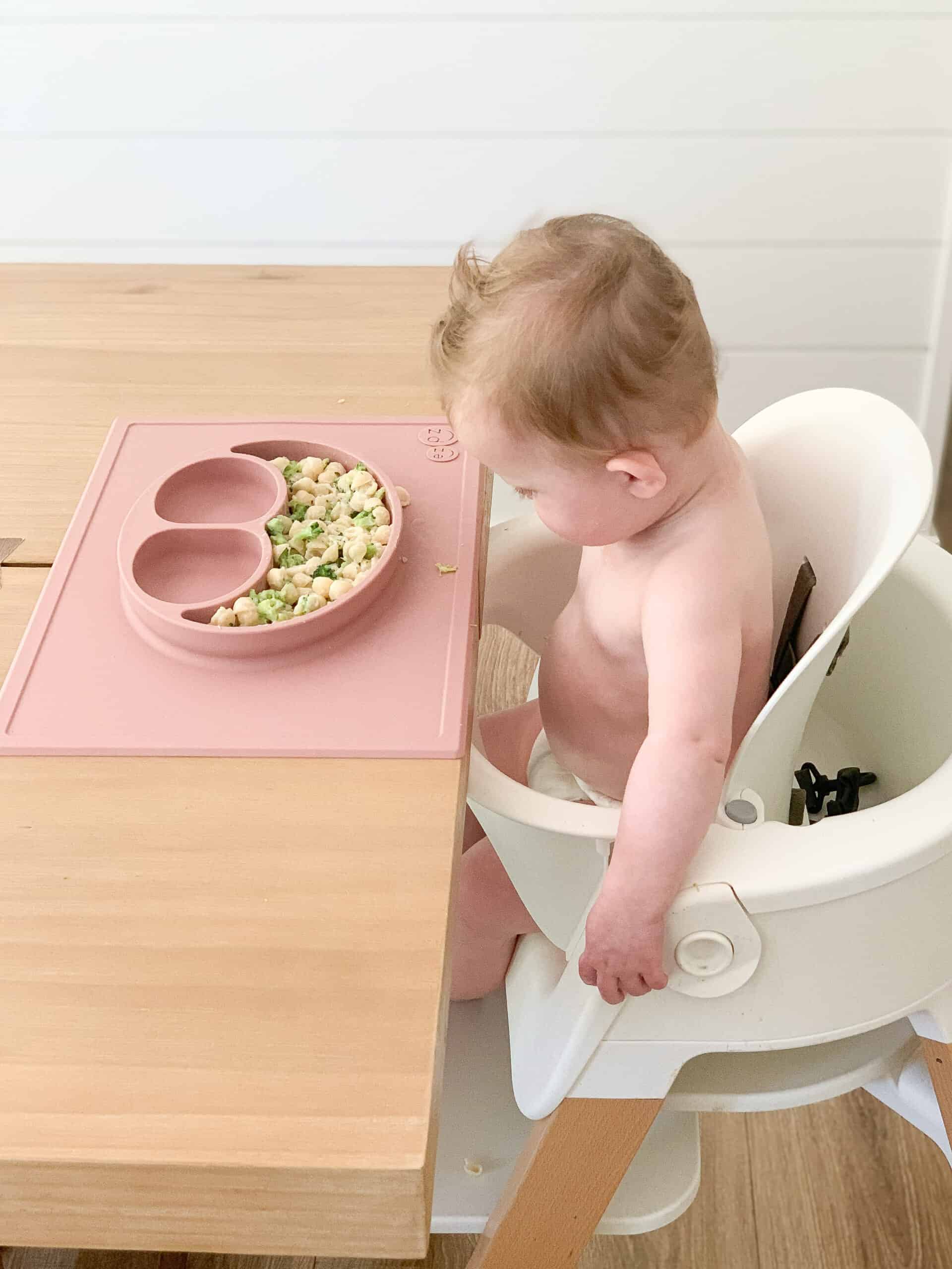 baby girl doing baby led weaning on pink Ezpz mat 