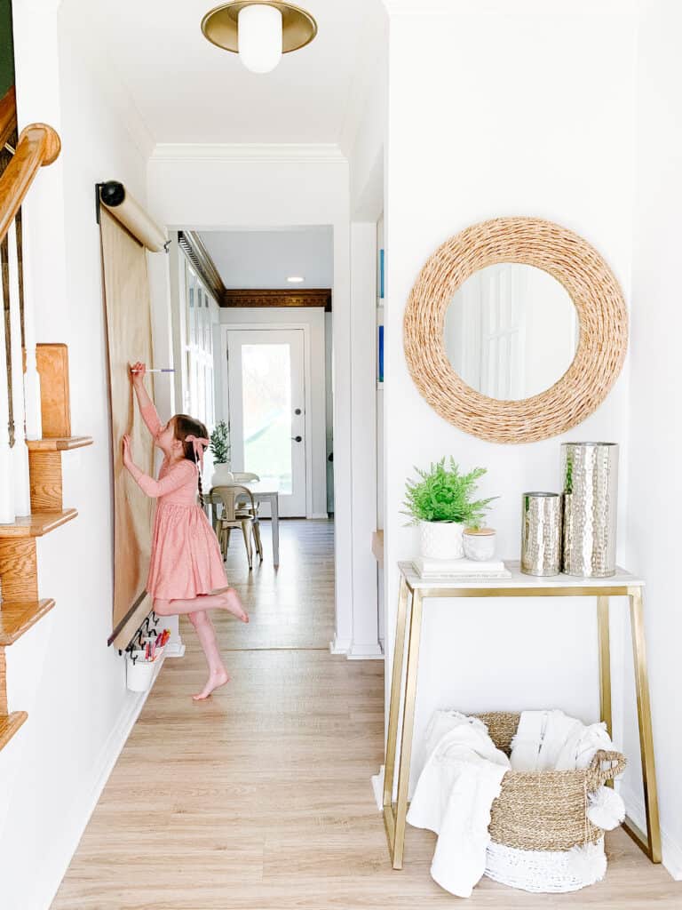 little girl coloring on a wall mounted easel 