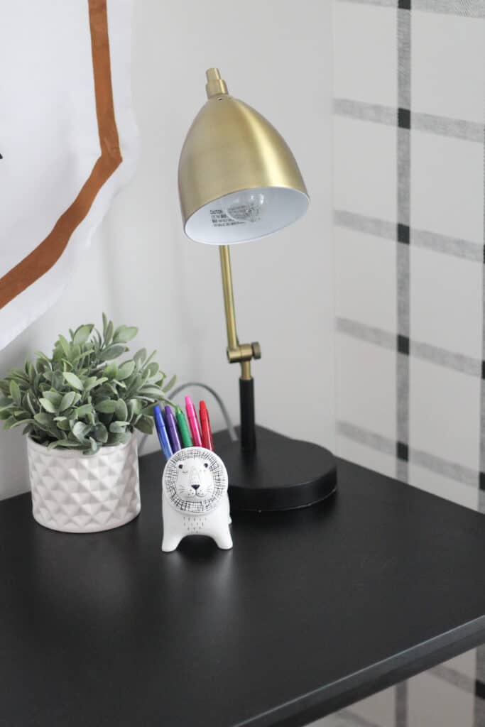 desk with pens and in animal cup and gold lamp