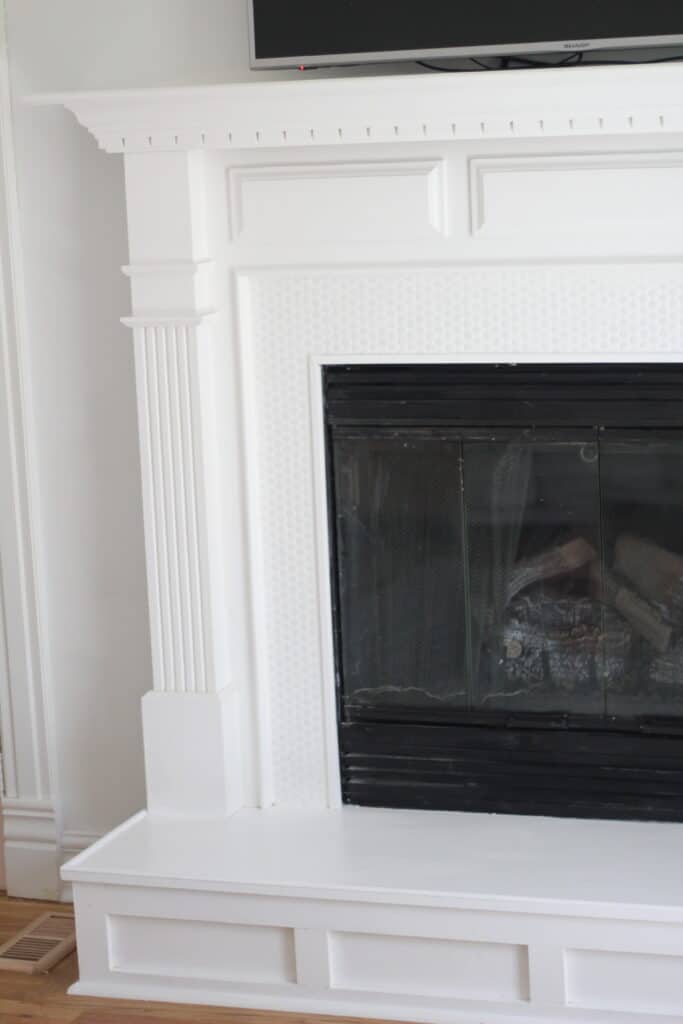 penny tile fireplace that is white with tv over it 