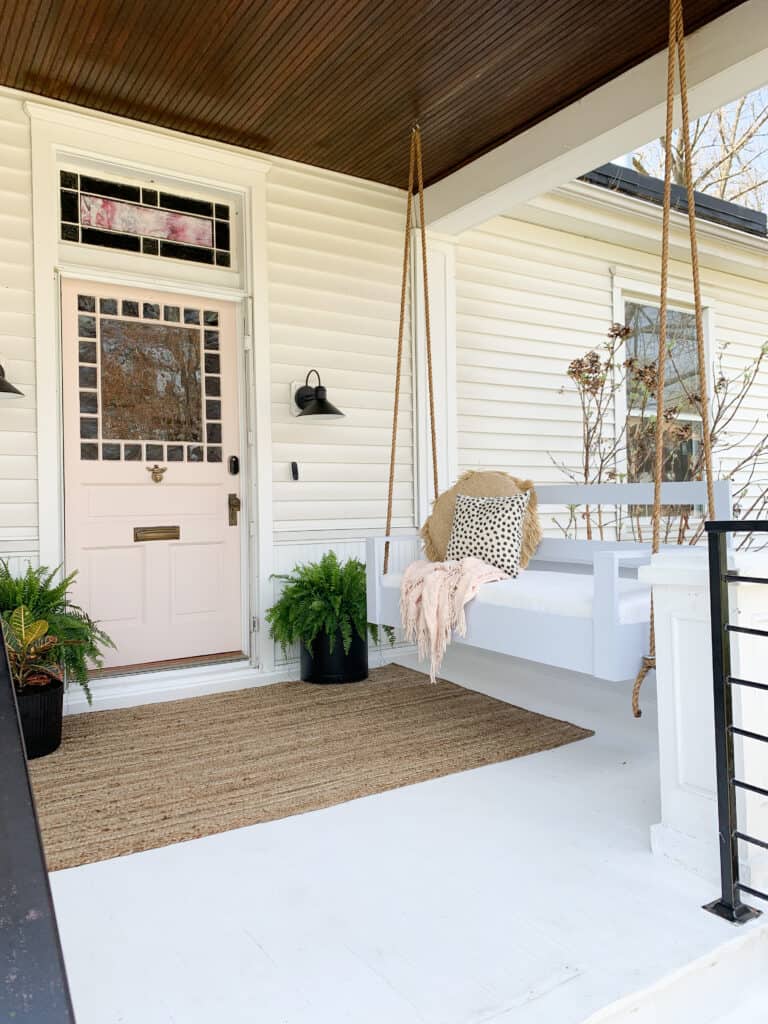 front porch with porch swing and pink door 