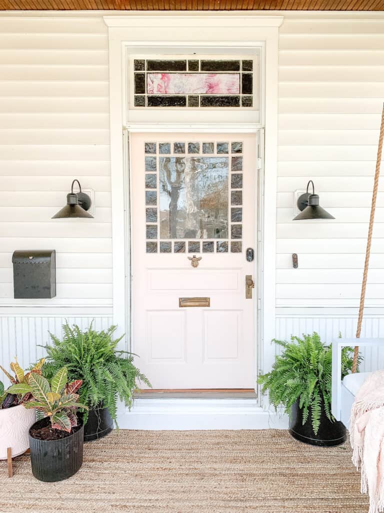 pink front door on house with black planters 