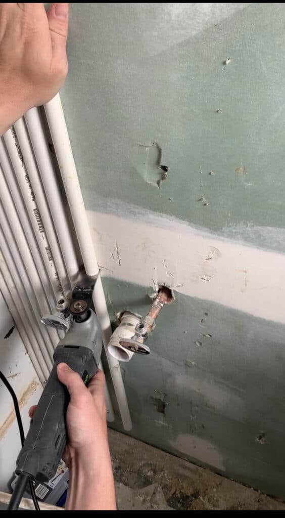 Cutting a PVC pipe wall with a multitool 