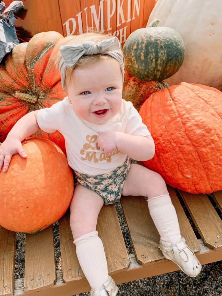 1 Year old girl sitting in pumpkins 