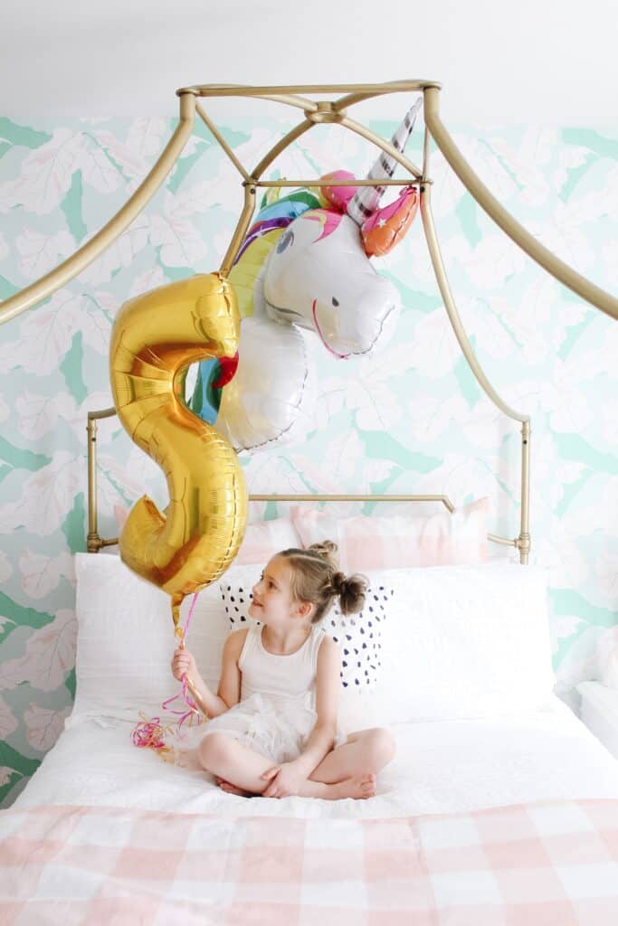 little girl on her bed with unicorn balloon 