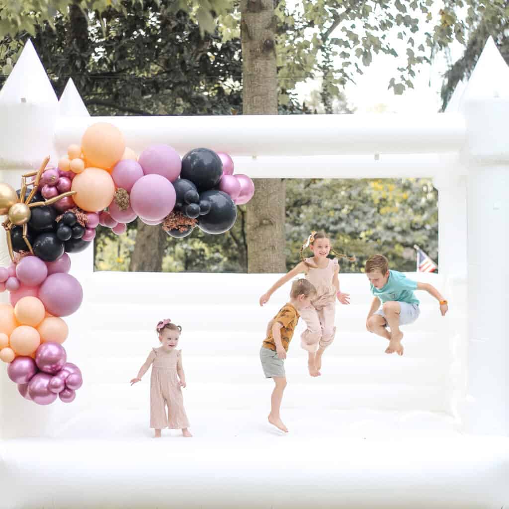 toddlers jumping on white bounce house