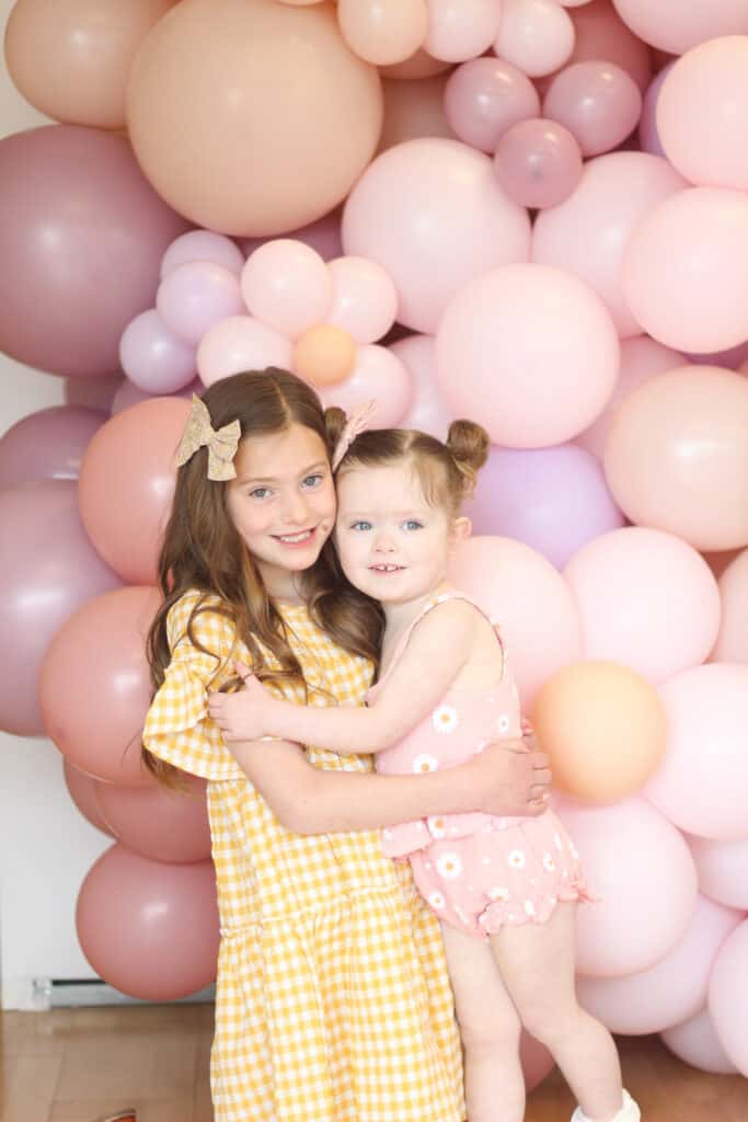 Sisters in front of balloon wall