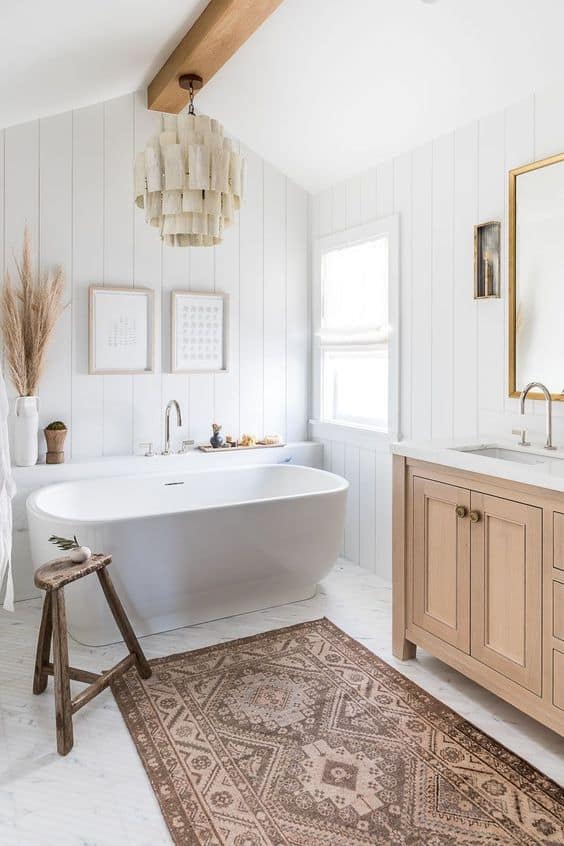 Natural adn bright bathroom with a white bathtub, brown/pink rug, and natural bathroom vanity.