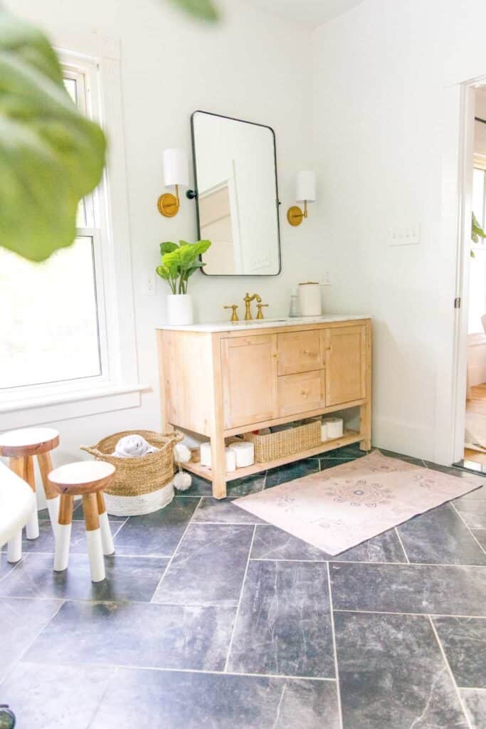 Wooden vanity, dark slate stone tile in a master bathroom.