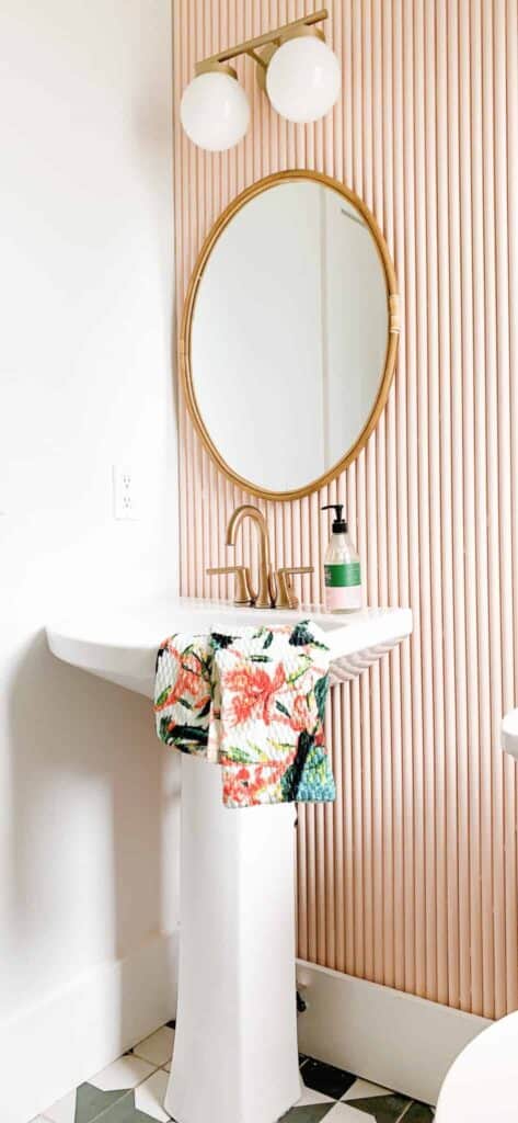 Pedestal sink with PVC backed DIY pink backsplash and gold mirror.