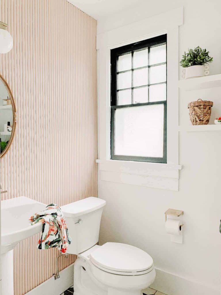 Pink bathroom with decorative items on a shelf.