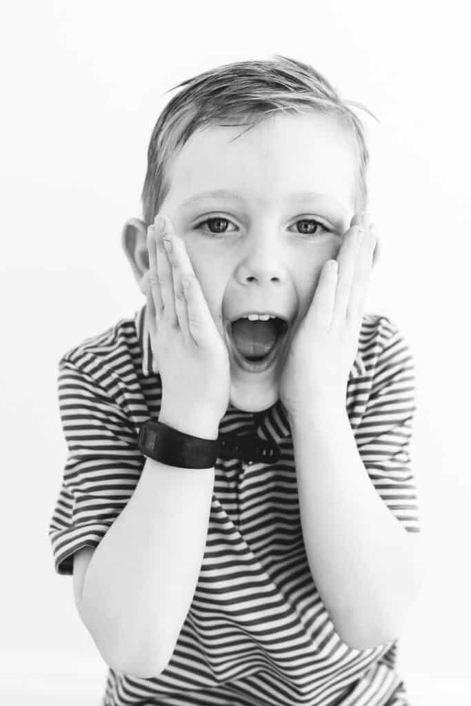 Little boy with hands to his face making a surprised face in black and white.
