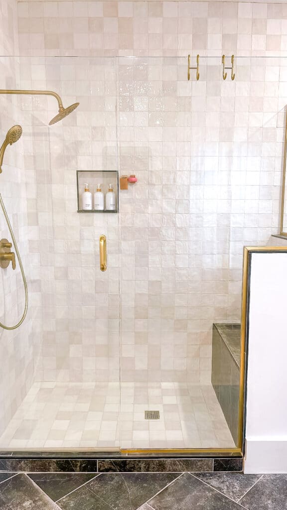 Natural stone shower with brass hardware accents.