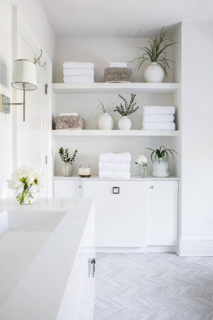 White bathroom with herringbone tile and built in open shelves.