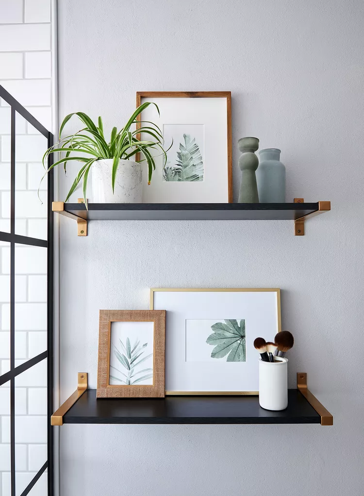 Modern black and gold bathroom shelves with decorative items.