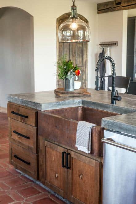 Dark wooden kitchen with limestone looking countertop and copper sink.