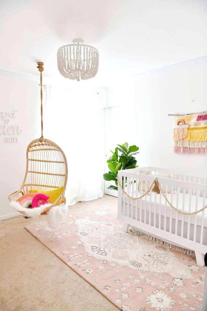Baby nursery with a hanging swing and rainbow accessories.