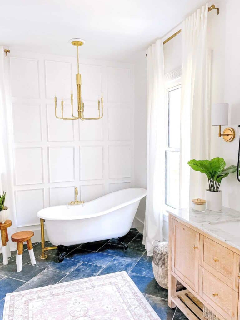 Clawfoot tub with picture frame molding in front of shower tile floor