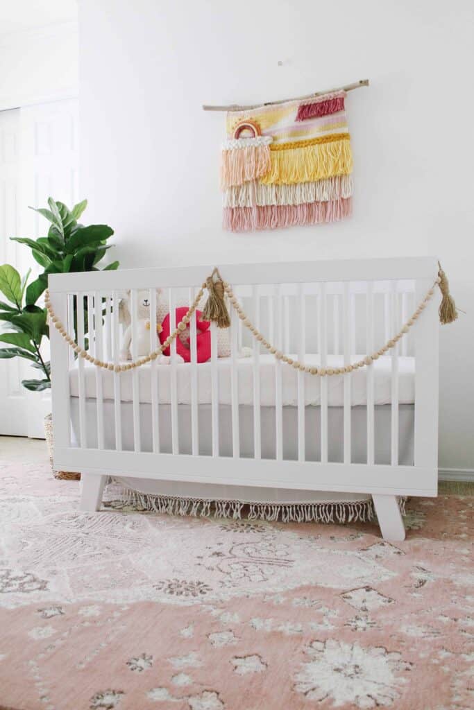 Baby nursery with rainbow boho wall hanging mural.