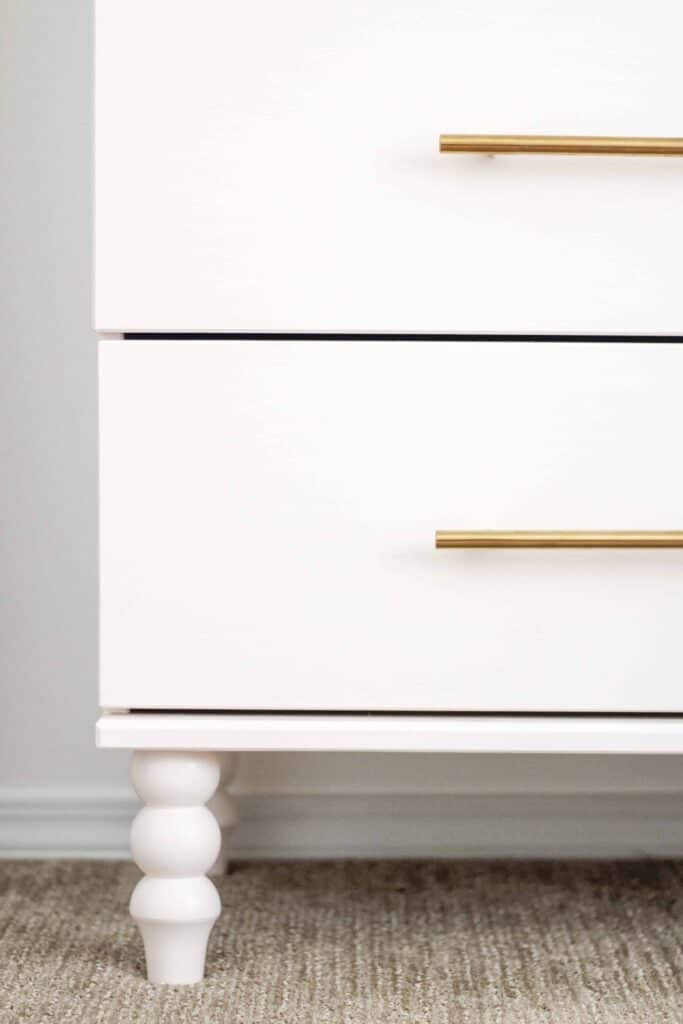 Close up of an IKEA dresser with custom built legs and gold hardware for a custom look.
