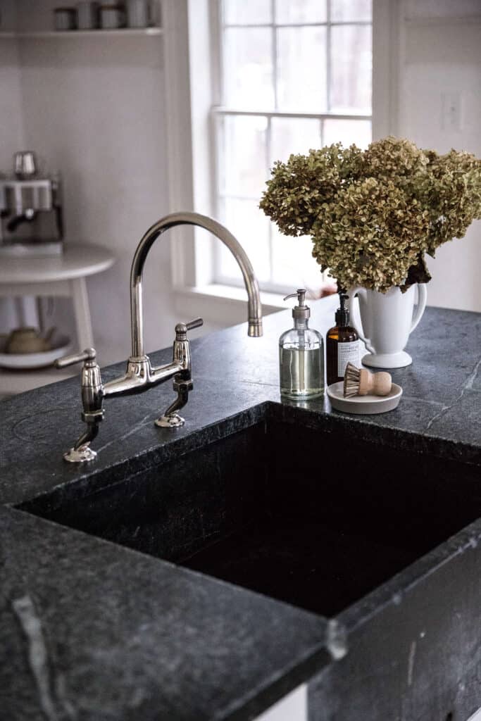 Dark natural stone sink with a vase of flowers.