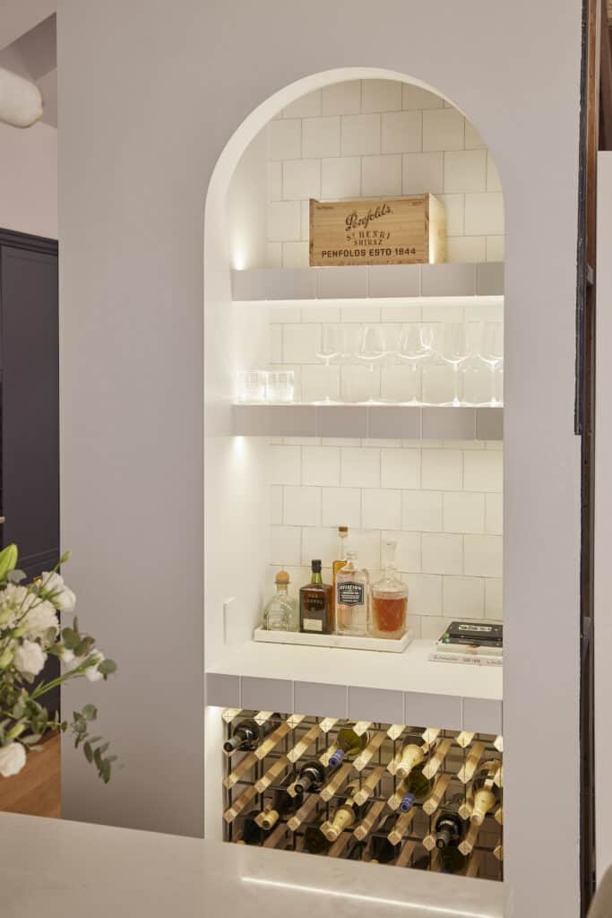 Arched bar with white tile and wine storage below.