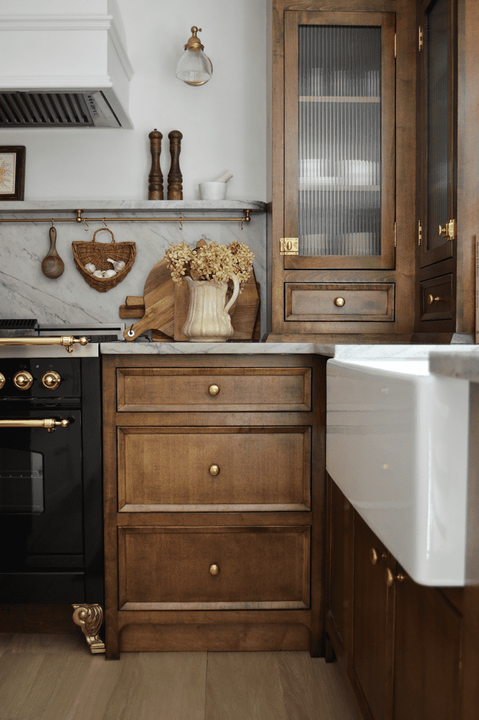 Dark wooden kitchen with natural light and white sink.