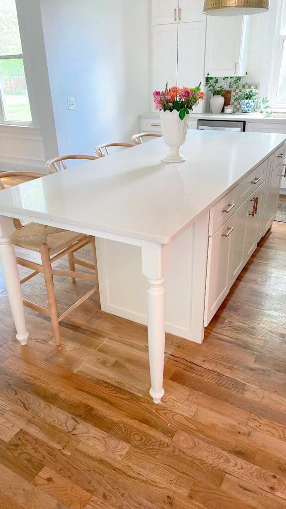 White kitchen island with apron front and tailored legs.