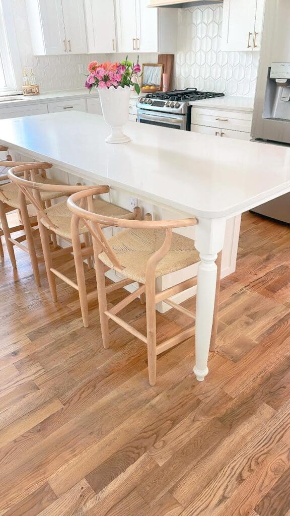 White kitchen with flowers and cane chairs.