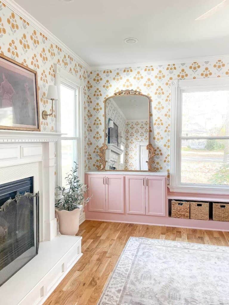 Playroom with pink cabinets, large gold mirror, and golden floral wallpaper.