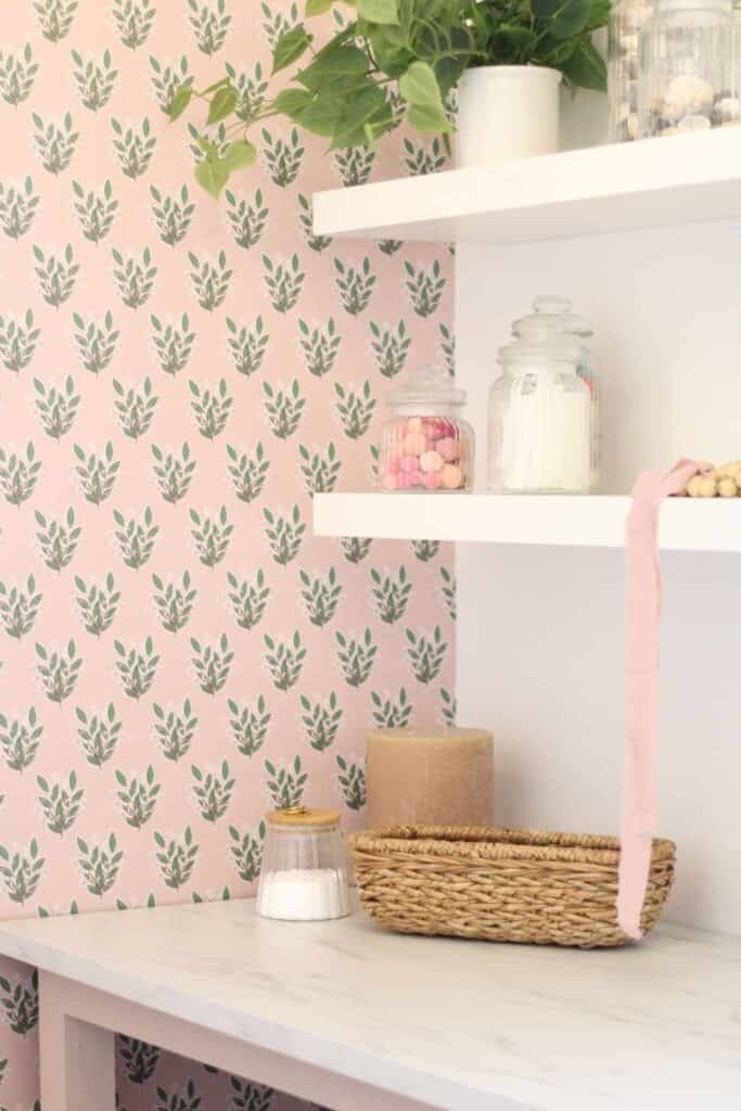 Shelf in a home office with green and pink floral wallpaper.