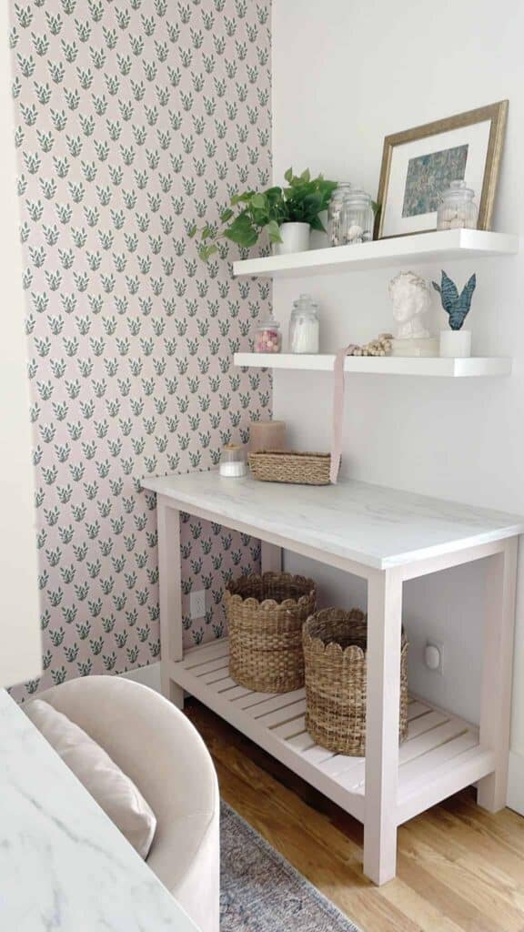 A DIY table complete with DIY floating white shelves and green and pink floral wallpaper.