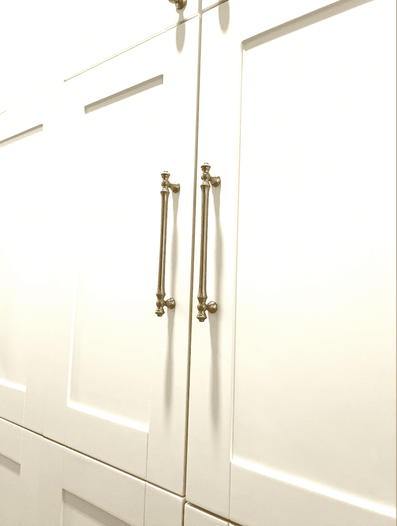 Close up of a white cabinet and bronze hardware pulls.