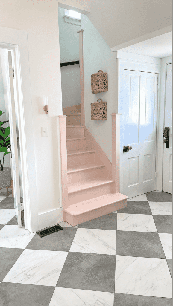 Pink staircase leading upstairs with grey and white marbled tile is seen in a mudroom.