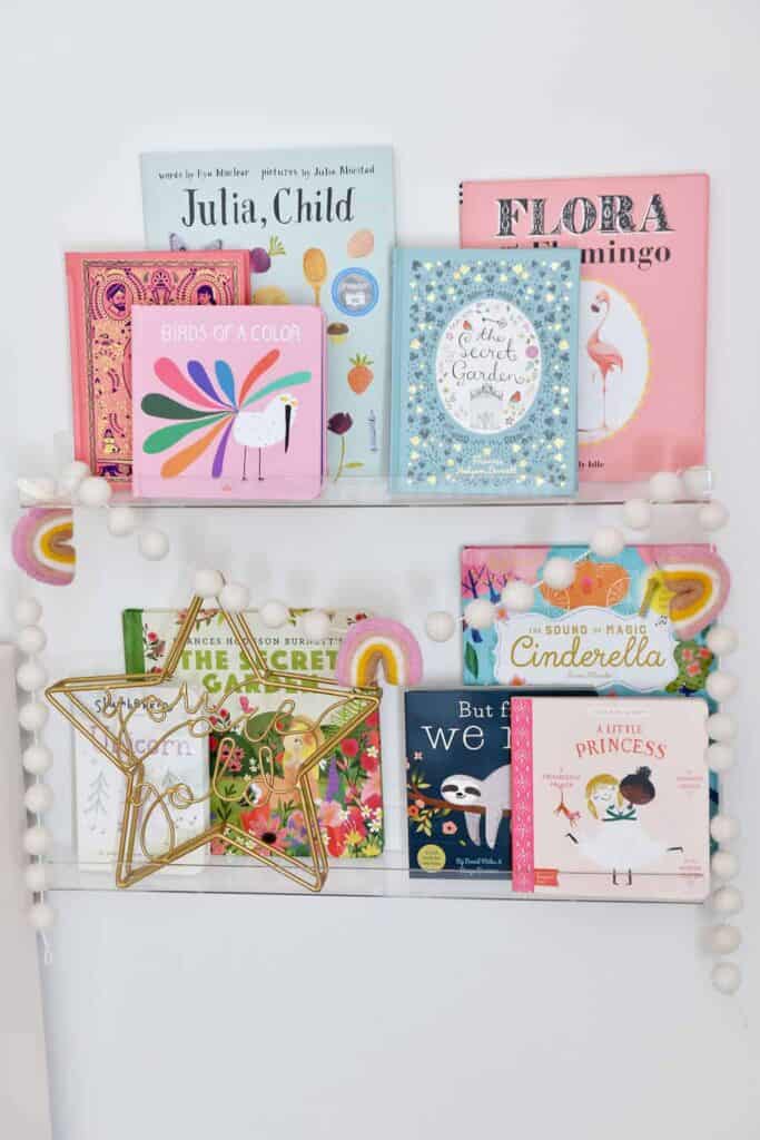 Decorative clear acrylic bookshelves are a great way to add decor in a toddler girl bedroom on a budget.