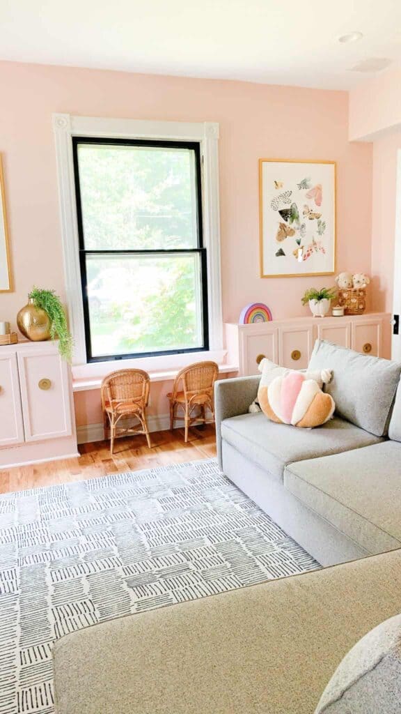 Pink playroom with pink cabinets, wicker chairs, and butterfly poster.